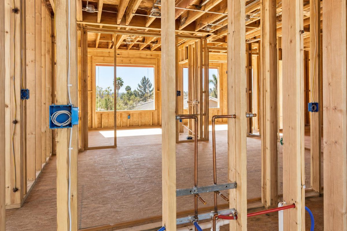 An unfinished interior with exposed studs, electrical boxes and rough plumbing