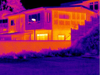 Infrared image of a house at night, its warm windows and walls in orange against a cool purple sky